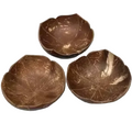 Three coconut shell bowls on a textured white surface